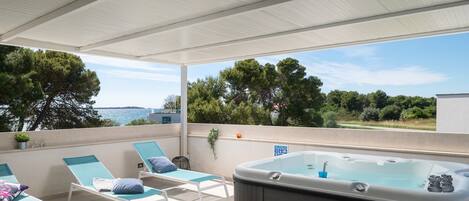 Una terraza en la azotea con sillones, una bañera de hidromasaje y vistas al mar.