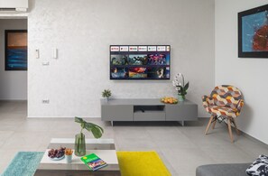 Una sala de estar moderna con un televisor de pantalla plana montado en la pared, mostrando diferentes servicios de streaming.