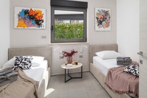 Un dormitorio moderno con dos camas, una mesita con un florero y obras de arte en las paredes.