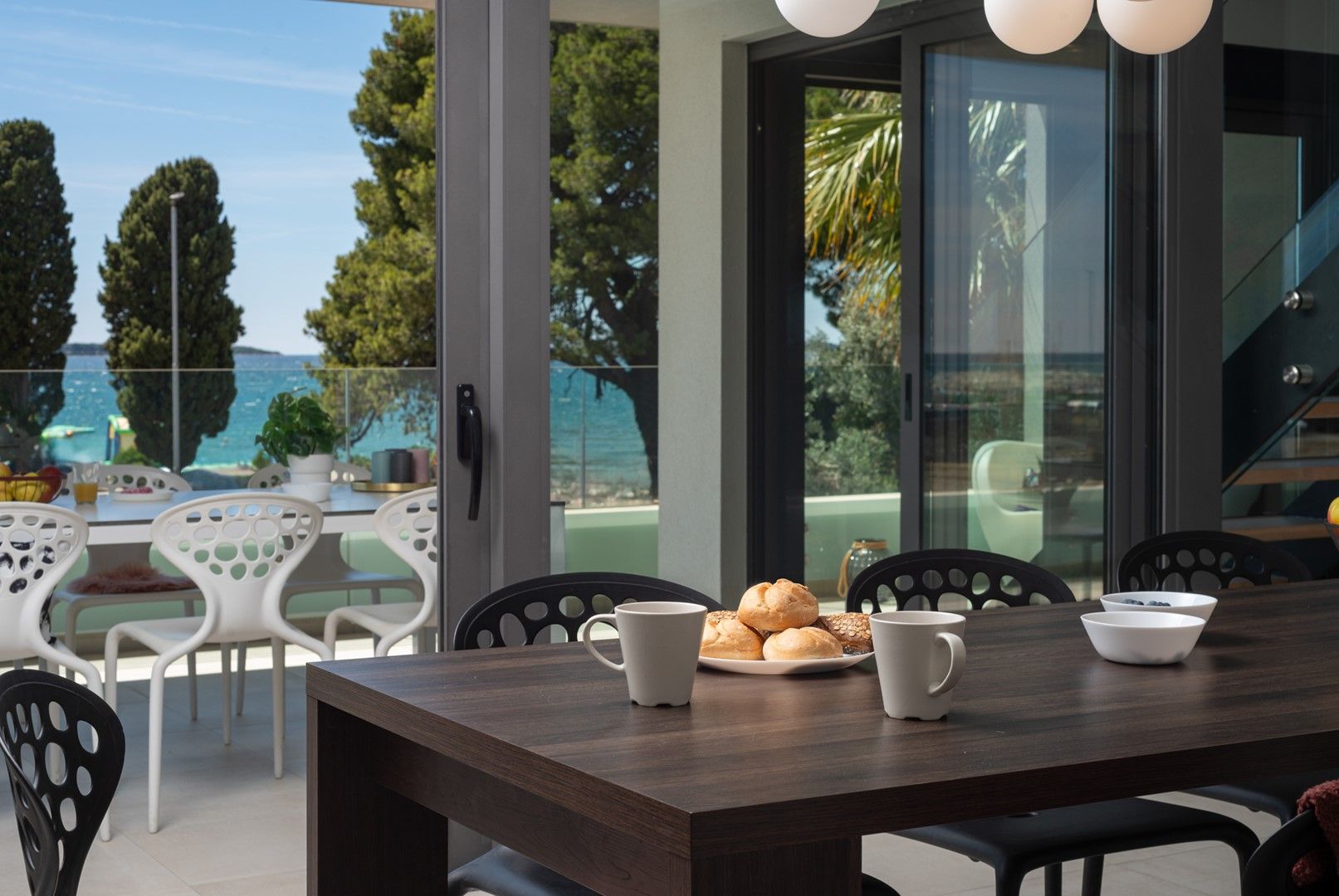 Ein Essbereich mit einem Tisch für zwei Personen, Blick auf das Meer und modernes Interieur.