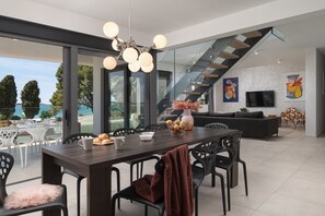 A modern dining area with a large table, chairs, and a chandelier.