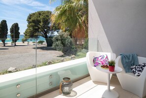 Un balcon avec une chaise blanche, une petite table ornée d’une plante et un vase décoratif.