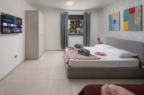 Ein modernes Schlafzimmer mit einem Bett, einem an der Wand montierten Fernseher und abstrakter Kunst.