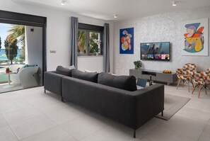 A modern living room with a grey sectional sofa, a flat-screen TV, and abstract art on the walls. - Villa Fasana 5 - luxury apartment with sea view and jacuzzi, for 7 persons. (Fažana)
