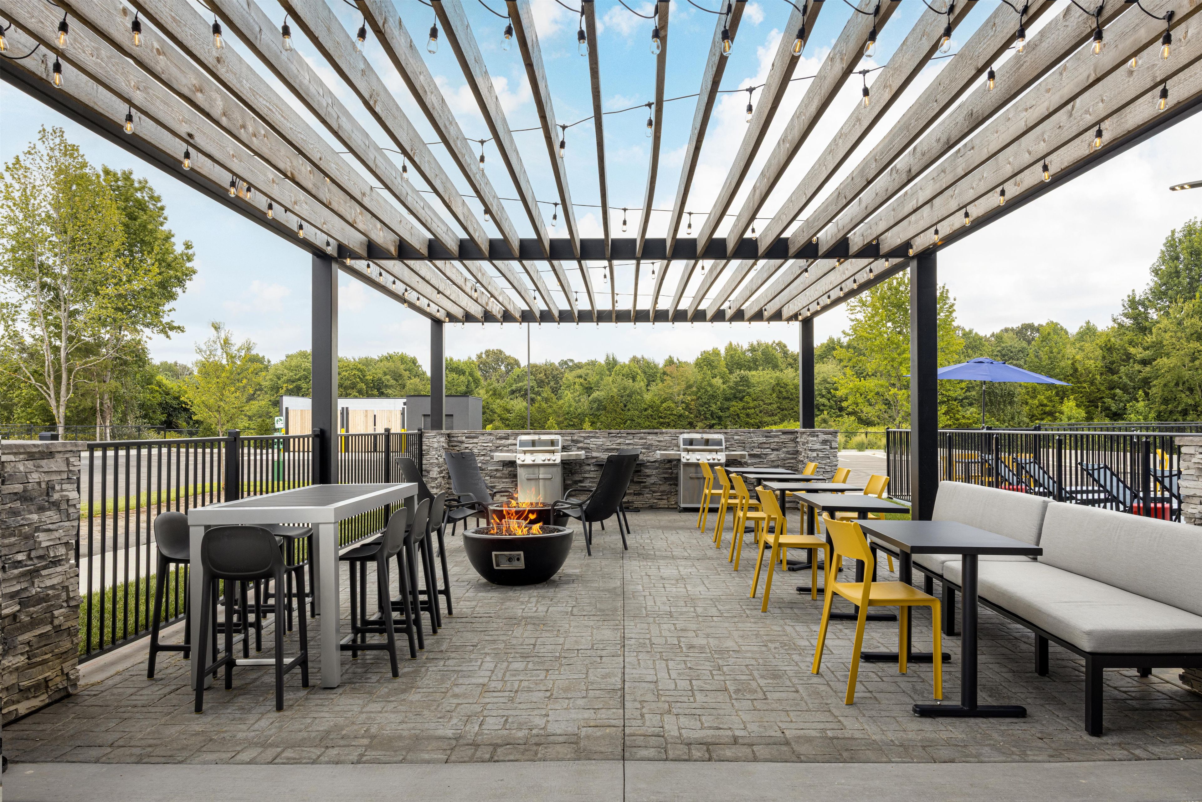 Une terrasse extérieure dotée d’une pergola, de coins salon, d’un foyer et de plusieurs barbecues.