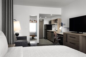 A hotel room with a bed, a desk, a chair, a television, and a bathroom visible through an open door. - Home2 Suites By Hilton Dickson (Dickson)