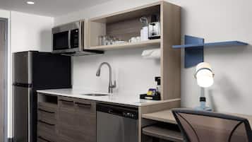 A modern kitchen with a built-in microwave, stainless steel appliances, a sink, and a compact dishwasher.