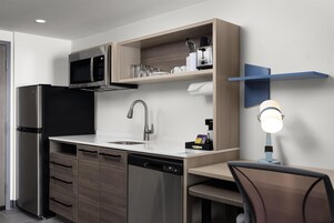Una cocina moderna con microondas integrado, electrodomésticos de acero inoxidable, un fregadero y un lavavajillas compacto.