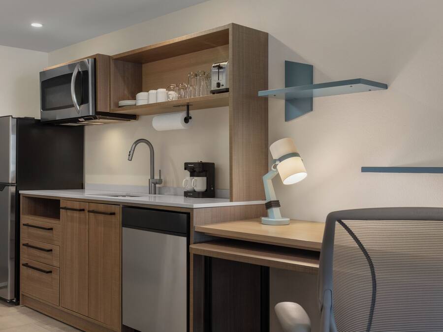 A modern kitchen with a built-in microwave, coffee maker, and a sink.