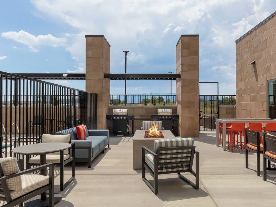 An outdoor patio with a fire pit, seating, and a view of the sky.