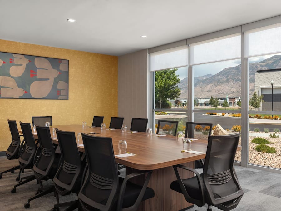 A conference room with a long table, chairs, and a large window with a mountain view.