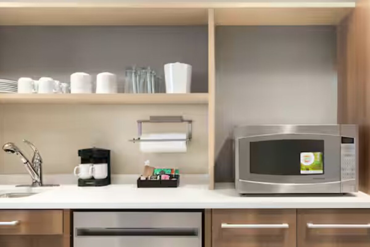 A modern kitchen with a stainless steel refrigerator, a microwave, and a coffee maker on the counter.