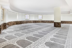 Une pièce spacieuse de forme circulaire, dotée d’un sol à motifs, de colonnes en marbre et de deux fenêtres.