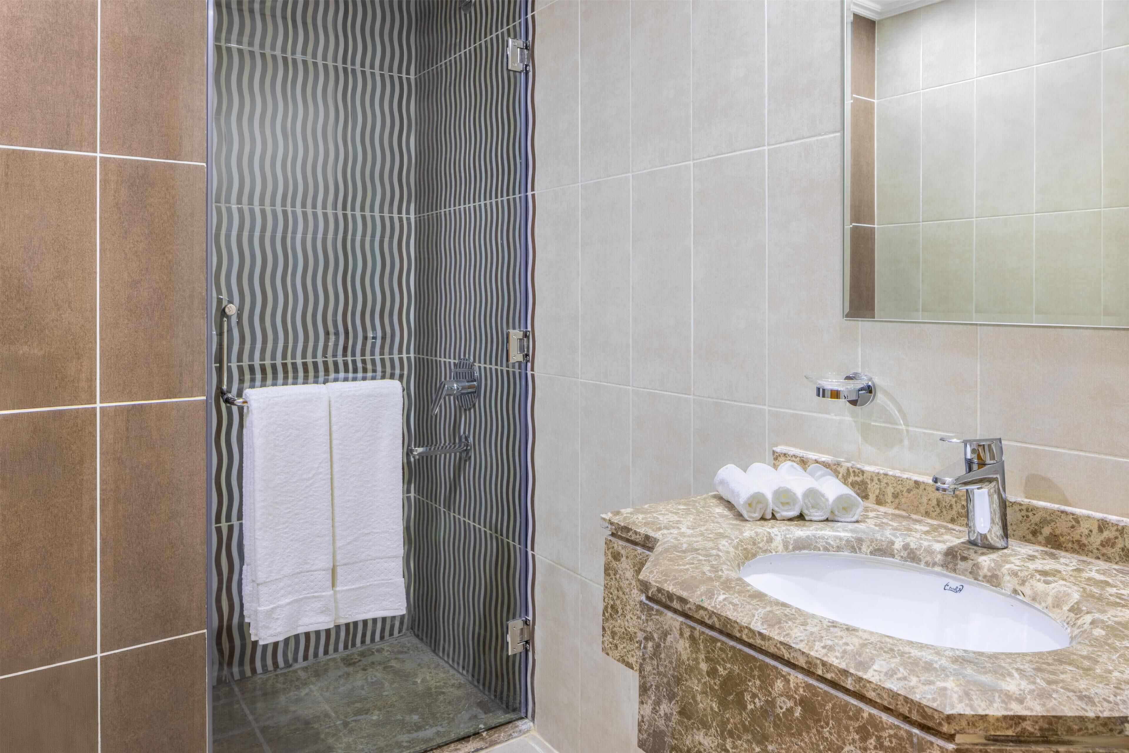 Un baño con ducha, lavabo y espejo.