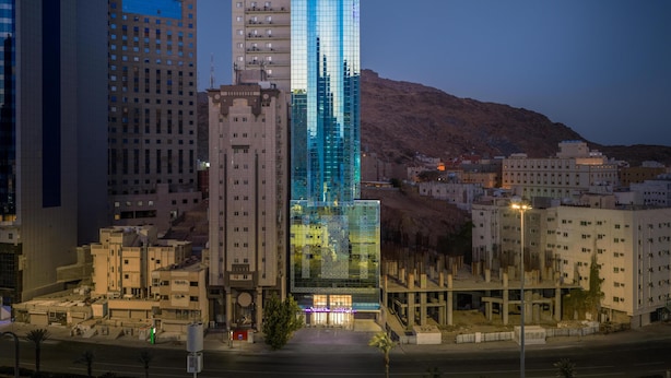 Un moderno edificio de gran altura con fachada de vidrio, rodeado de otros edificios.