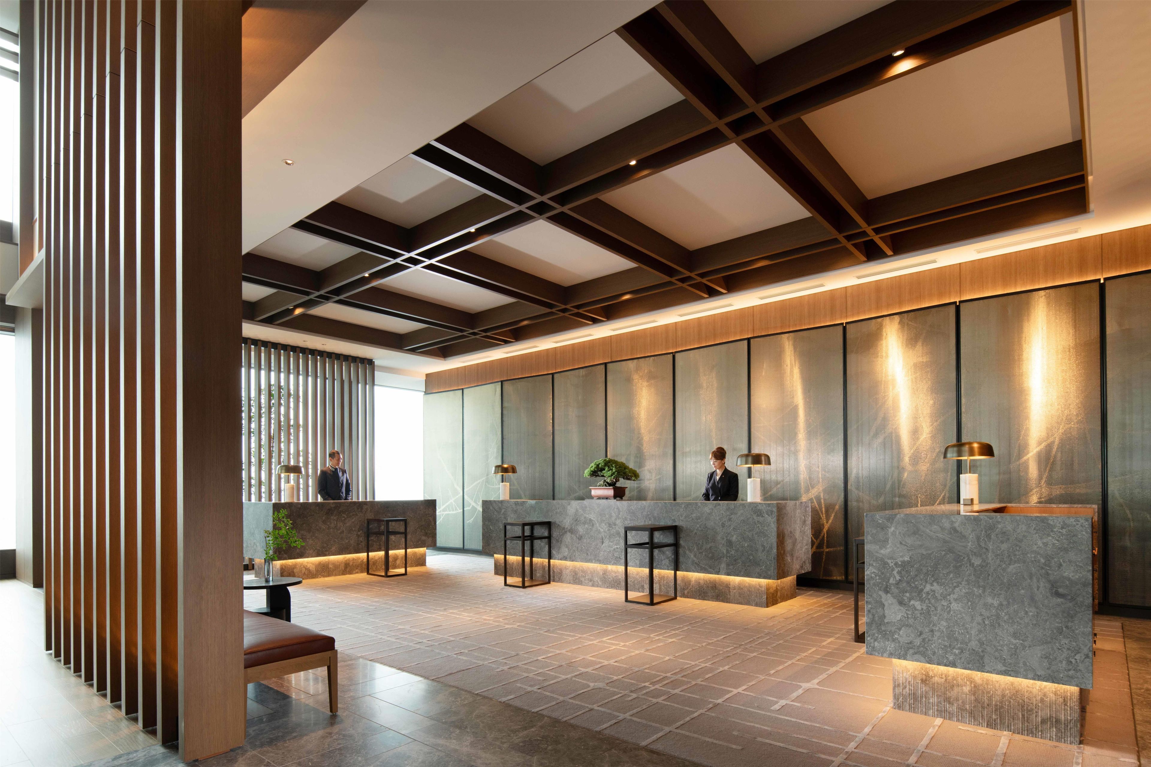A modern reception area with a reception desk, seating, and a large window.
