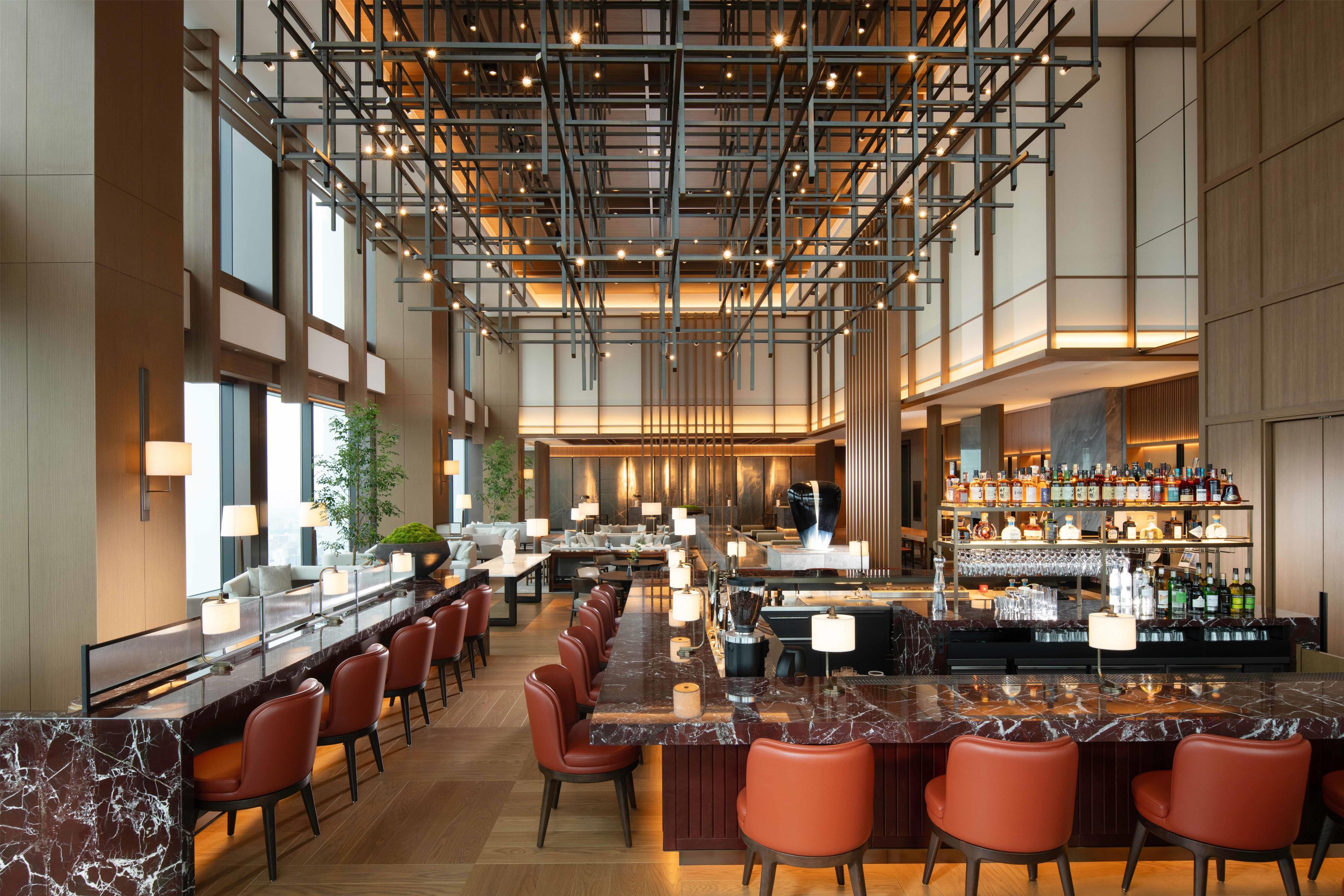 A modern bar area with a long counter, multiple seating options, and a well-stocked bar.