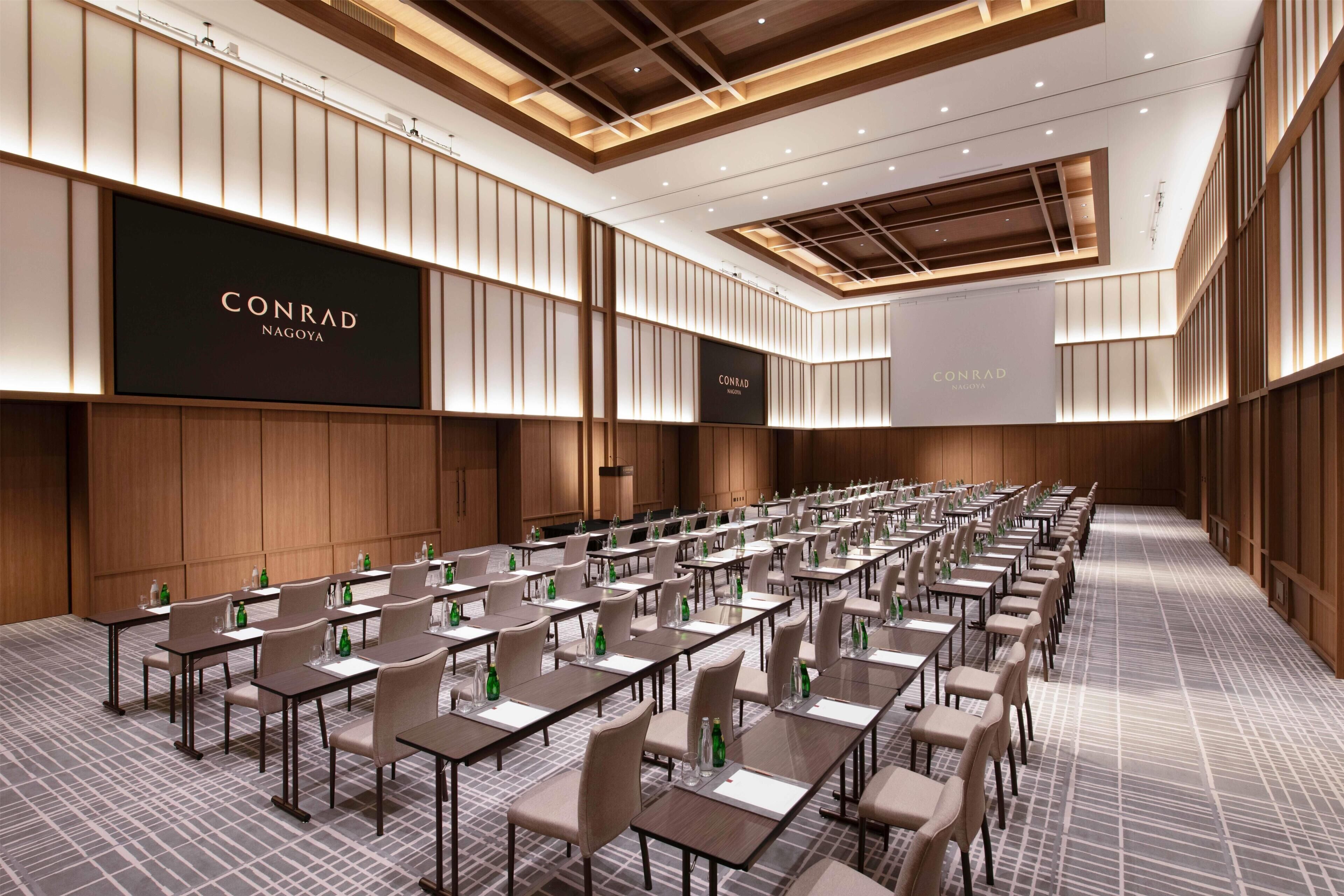 A conference room with multiple tables and chairs, branded with 'CONRAD NAGOYA' on the walls.
