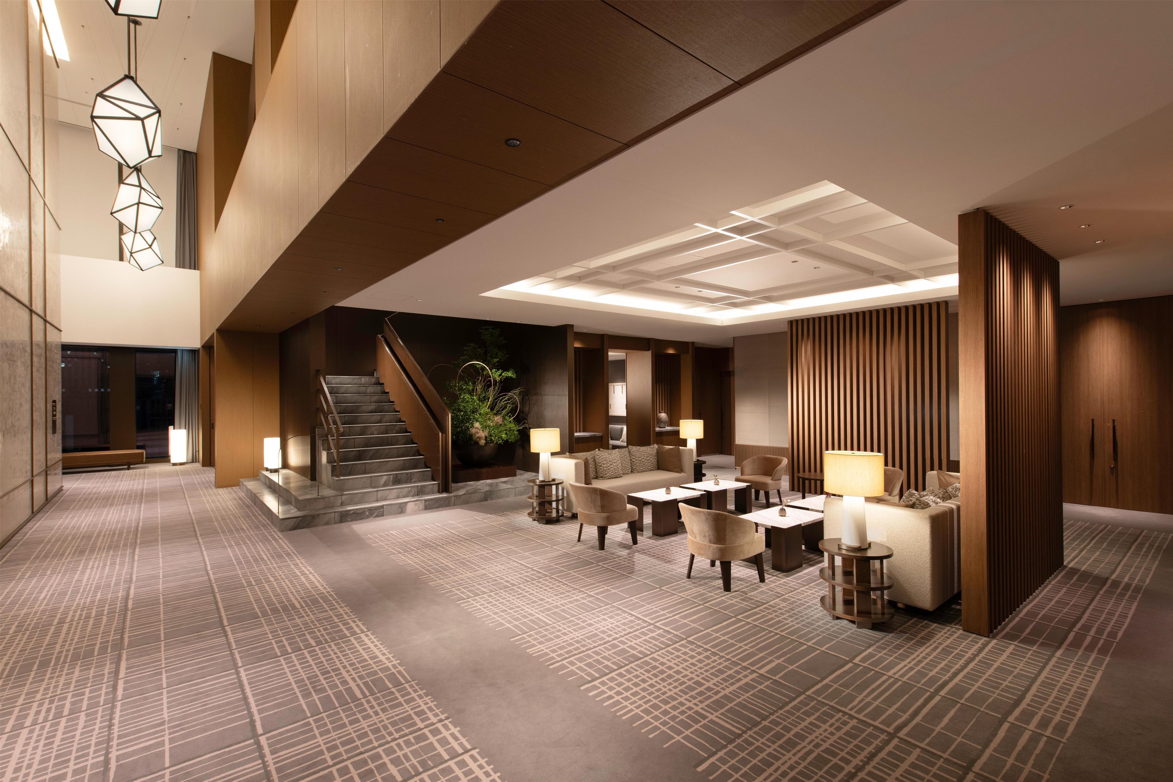 Un hall d’hôtel avec un escalier, un espace salon et un comptoir d’accueil.