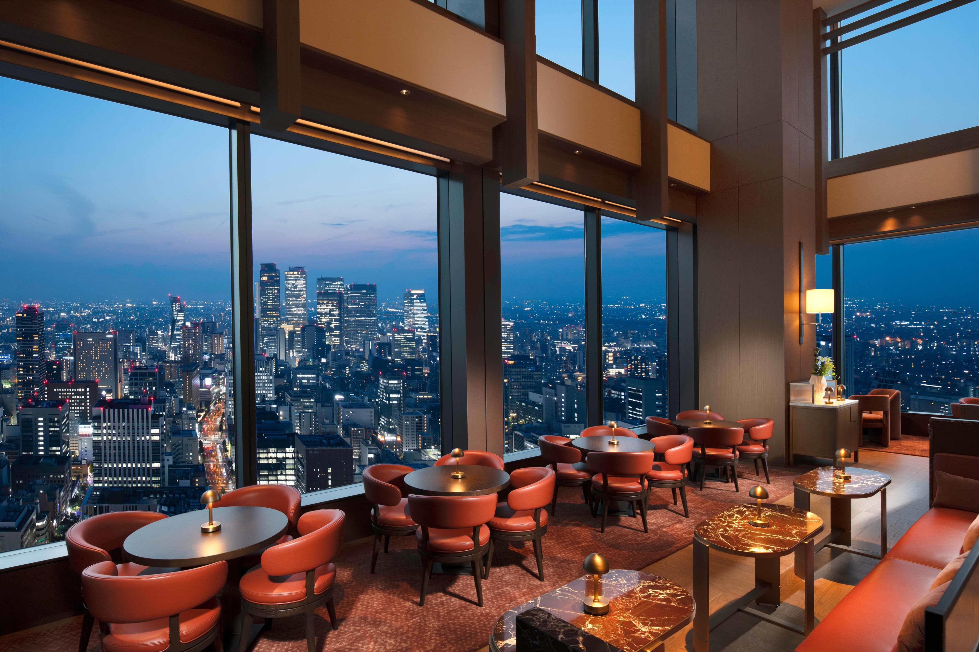A high-rise interior with panoramic city views, multiple seating areas, and modern decor.