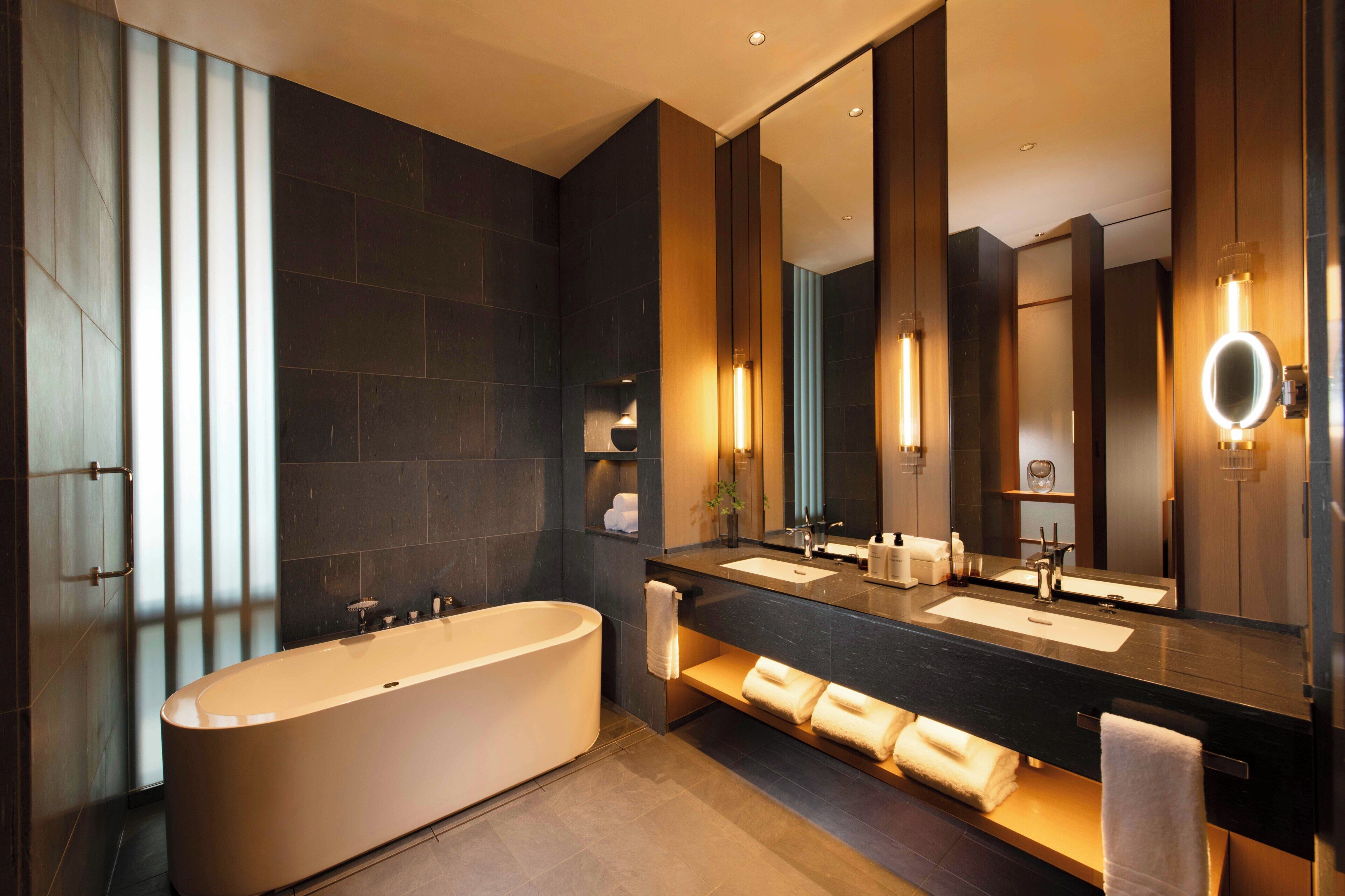 A modern bathroom with a freestanding bathtub, dual sinks, and a large mirror.