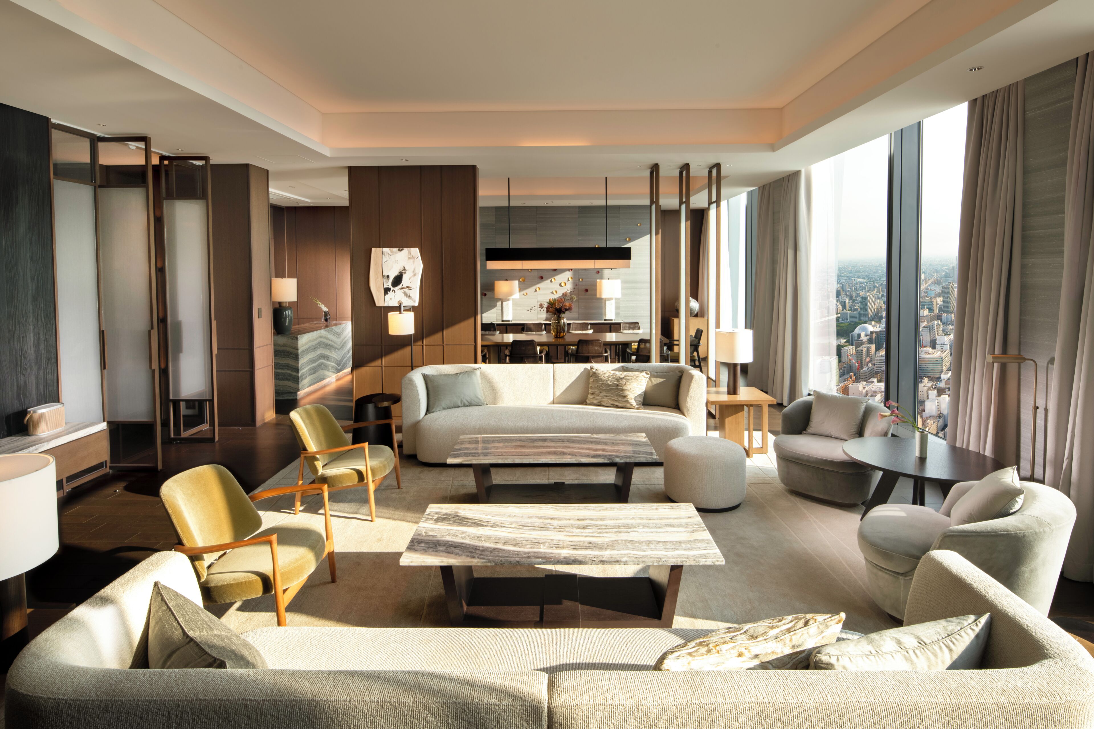 Habitación de hotel moderna con una cama grande, un sofá, una mesa de comedor y vistas a la ciudad.