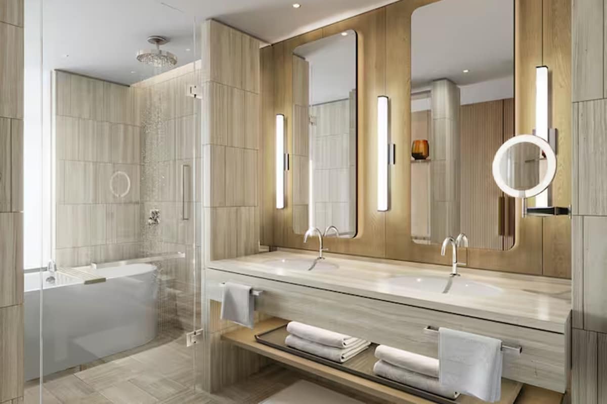 A modern bathroom with a large mirror, two sinks, a bathtub, and a shower.