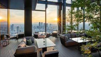 Un lounge en la azotea con vistas a la ciudad, amueblado con sofás, mesas y sillas.