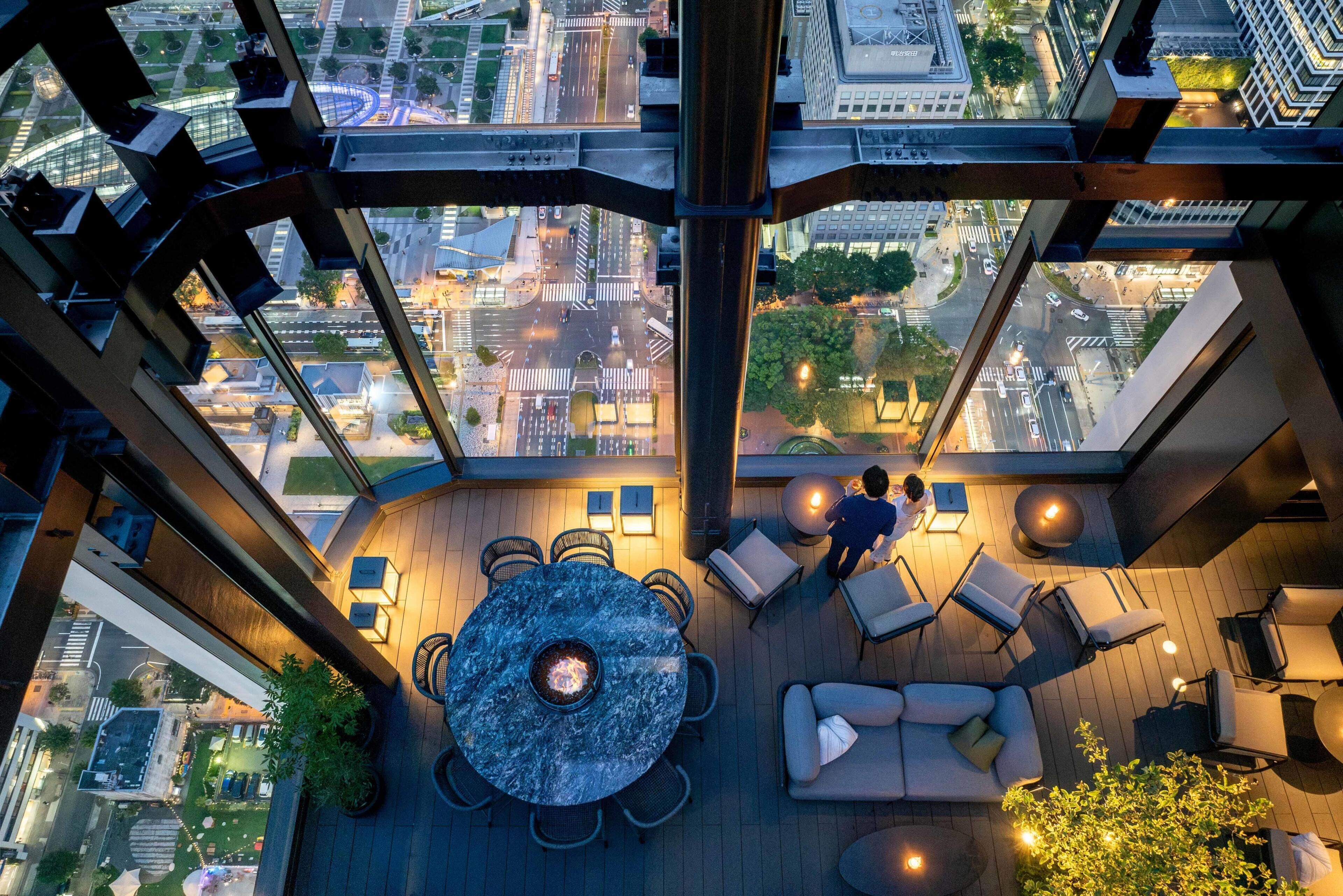 Une terrasse sur le toit avec une table ronde, des sièges et un foyer.