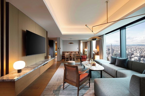 Una habitación de hotel moderna con vistas a la ciudad, un comedor y una sala de estar con sofá y sillones.