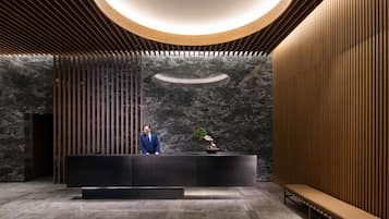 A reception area with a modern design, featuring a reception desk, a bench, and a large circular light fixture.