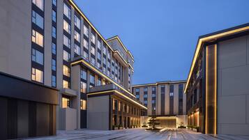 Un hotel moderno con un patio central, varios pisos y una fachada bien iluminada.