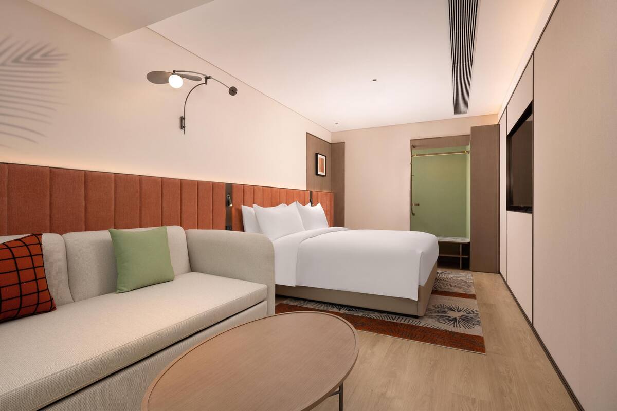 Una habitación de hotel moderna con cama, sofá y una pequeña mesa.