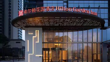 El exterior del Hilton Garden Inn con un diseño moderno, que presenta una entrada curva y ventanas amplias.