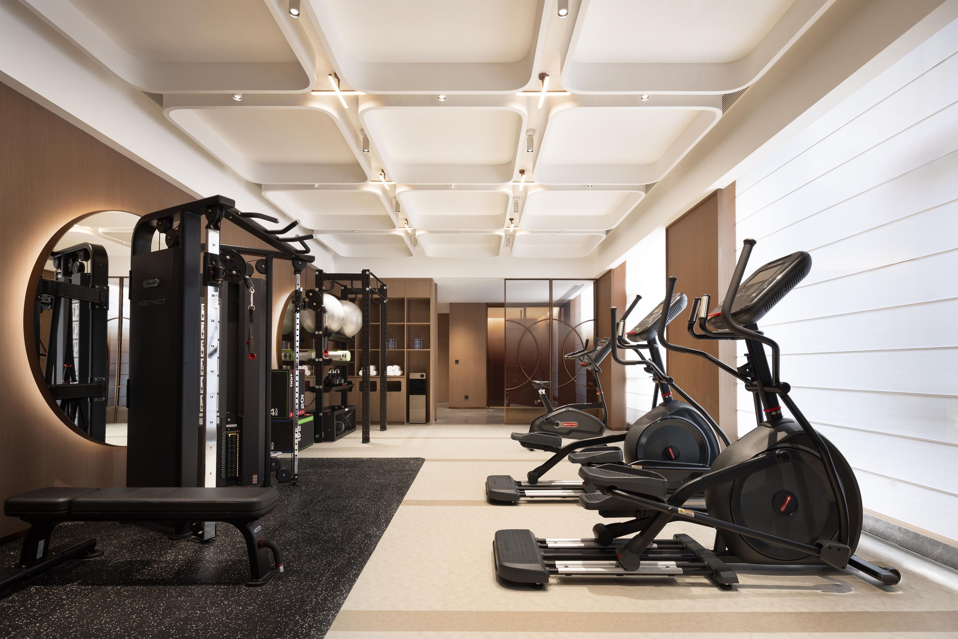 Un gimnasio moderno con varios equipos de ejercicio, incluyendo una cinta de correr, una elíptica y máquinas de pesas.