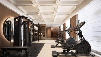 Un gimnasio moderno con varios equipos de ejercicio, incluyendo una cinta de correr, una elíptica y máquinas de pesas.