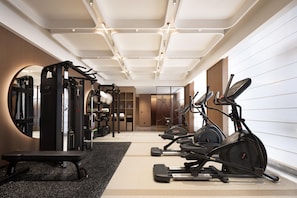 A modern gym with various exercise equipment, including a treadmill, elliptical, and weight machines. - Hilton Garden Inn Chengdu Huaxi Wuhou Shrine (Nanchong)