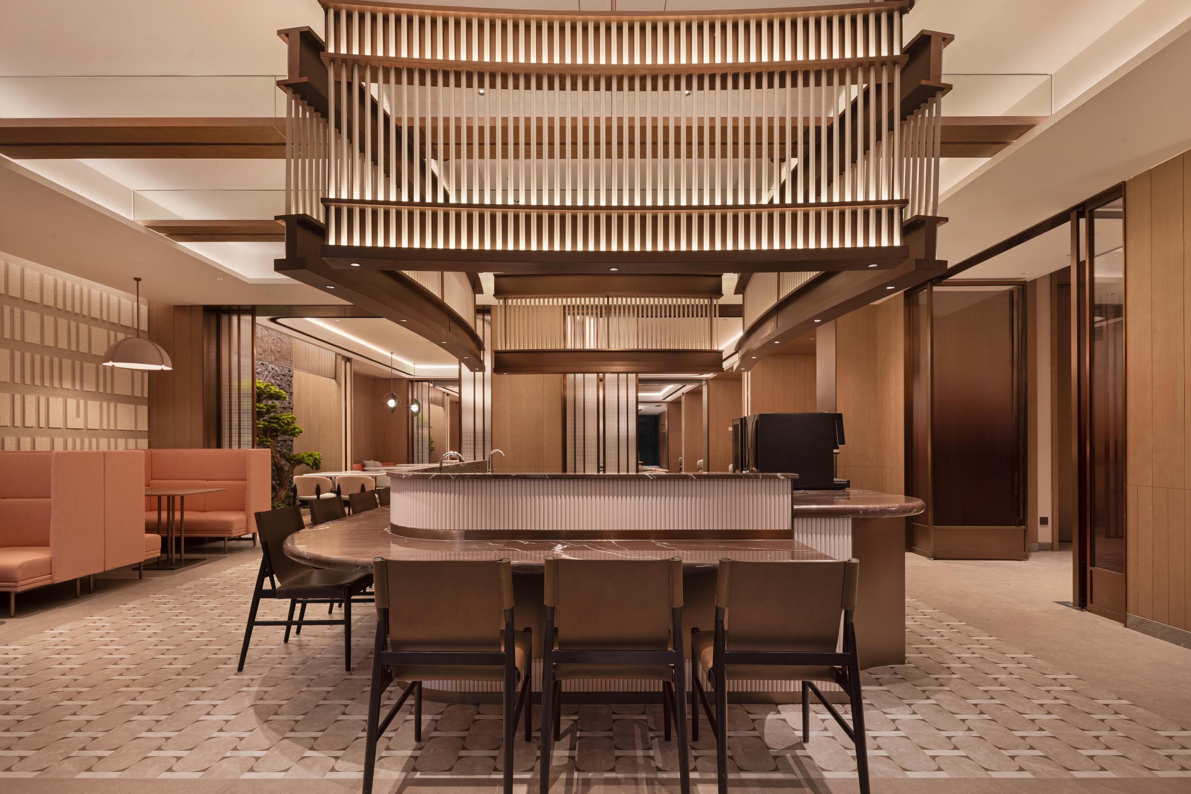 A modern interior with a central bar area, seating arrangements, and a staircase.