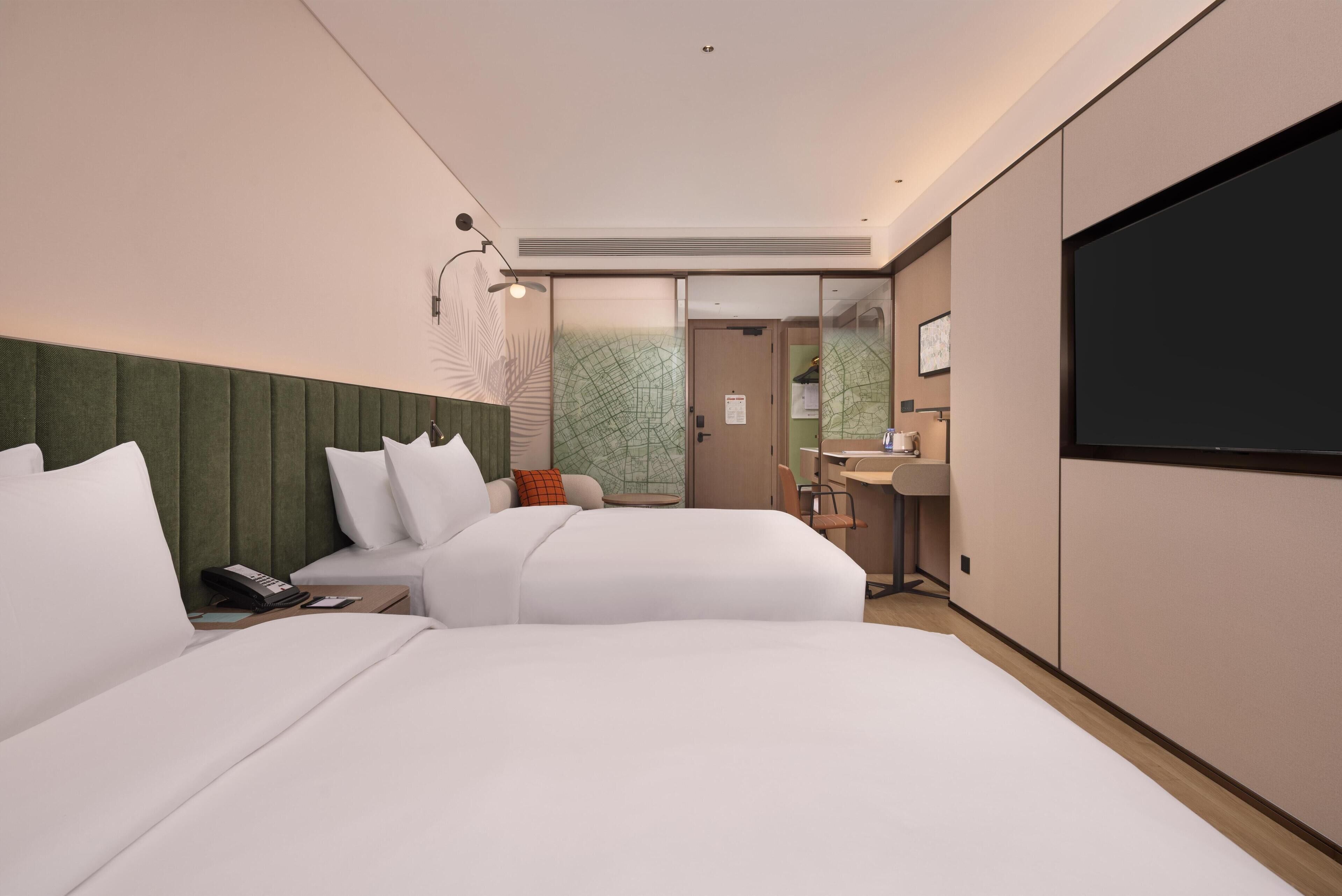 A modern hotel room with a large bed, a desk, a flat-screen TV, and a bathroom.