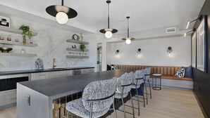 Une cuisine moderne avec un dosseret en marbre, un îlot central et des luminaires suspendus.