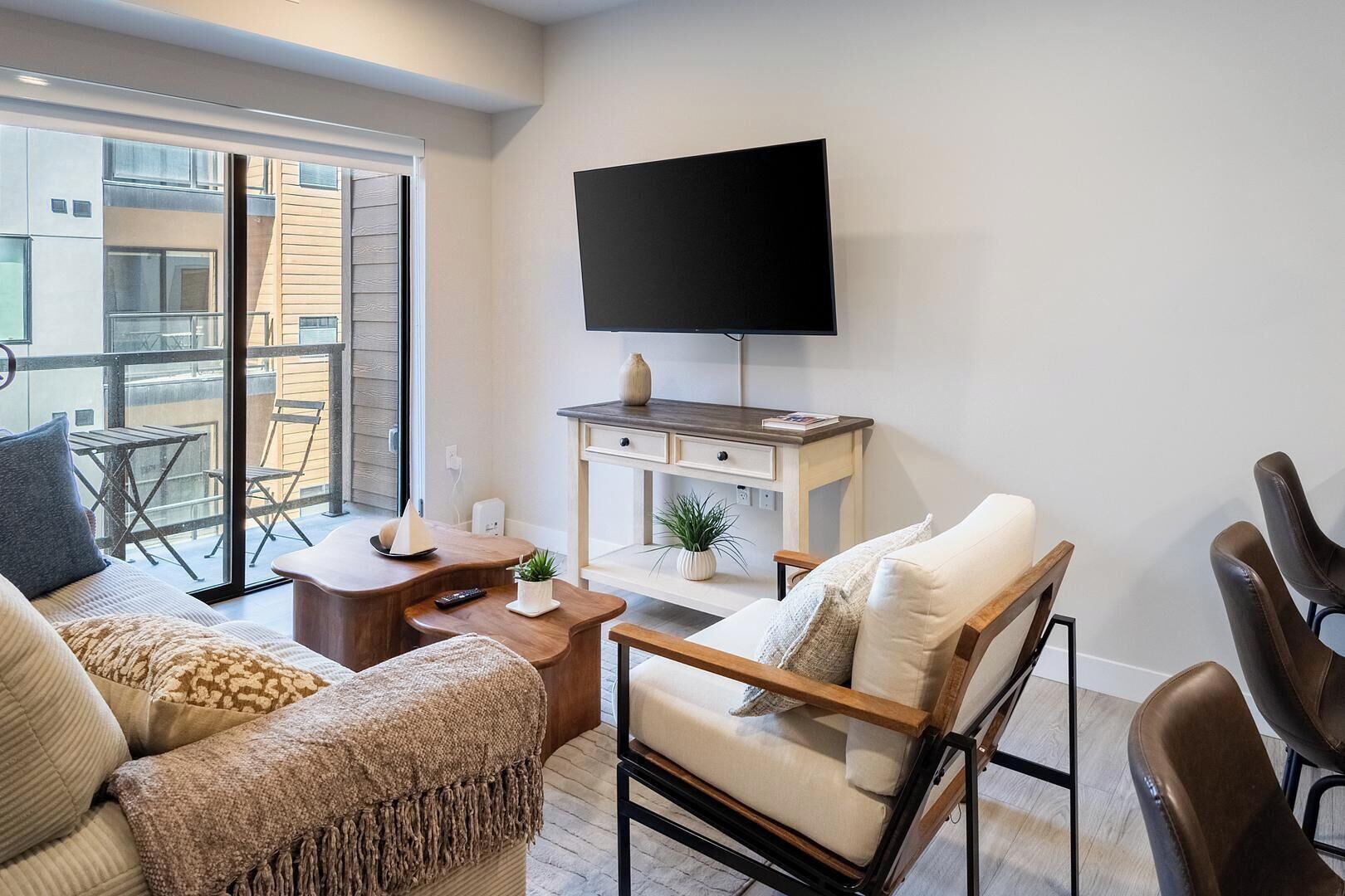 Un salon moderne avec un canapé, un fauteuil, une table basse, un téléviseur et un balcon offrant une vue agréable.