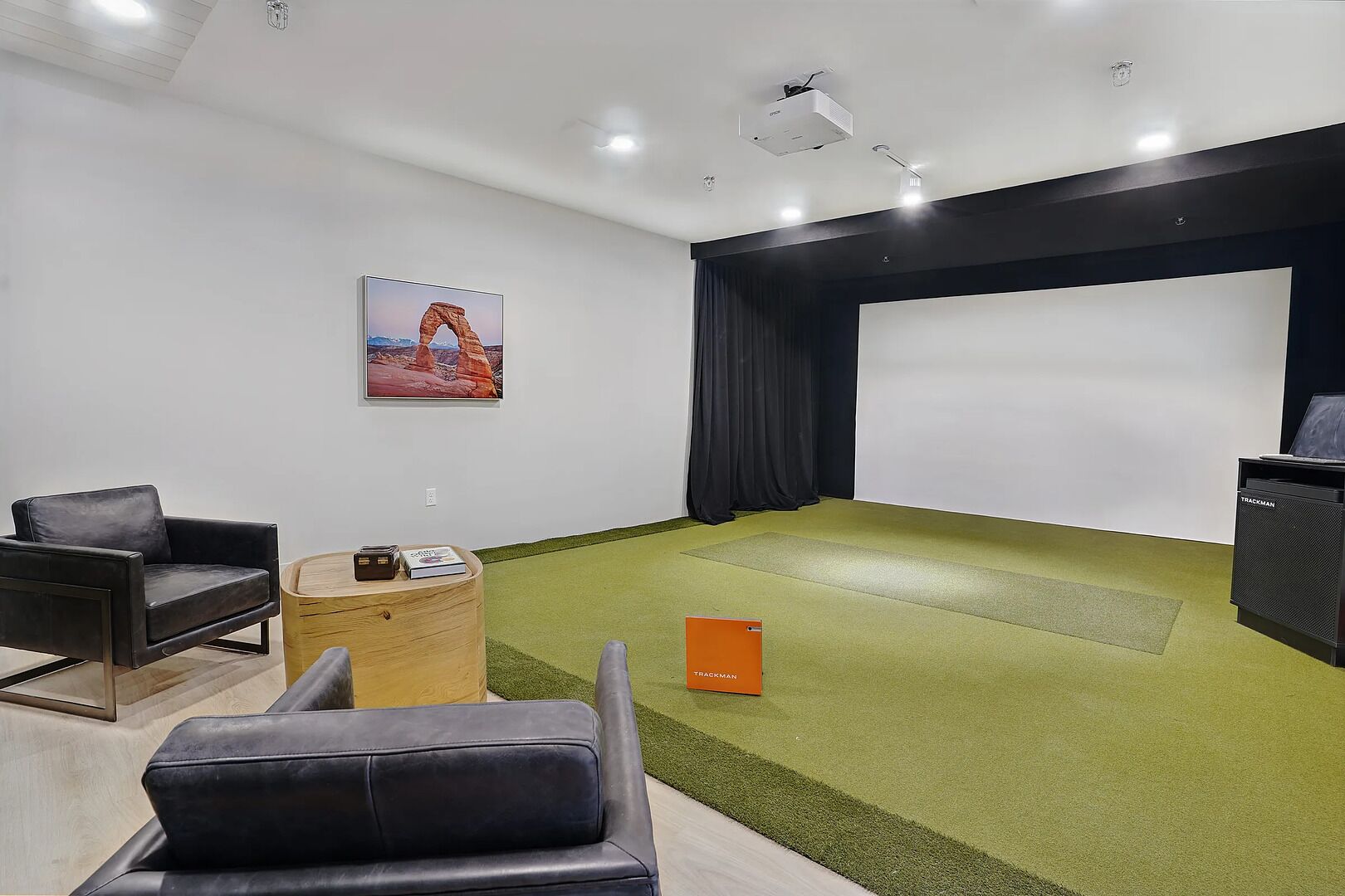 Ein modernes Zimmer mit Projektionsschirm, einer Couch, einem kleinen Tisch und Teppichboden.