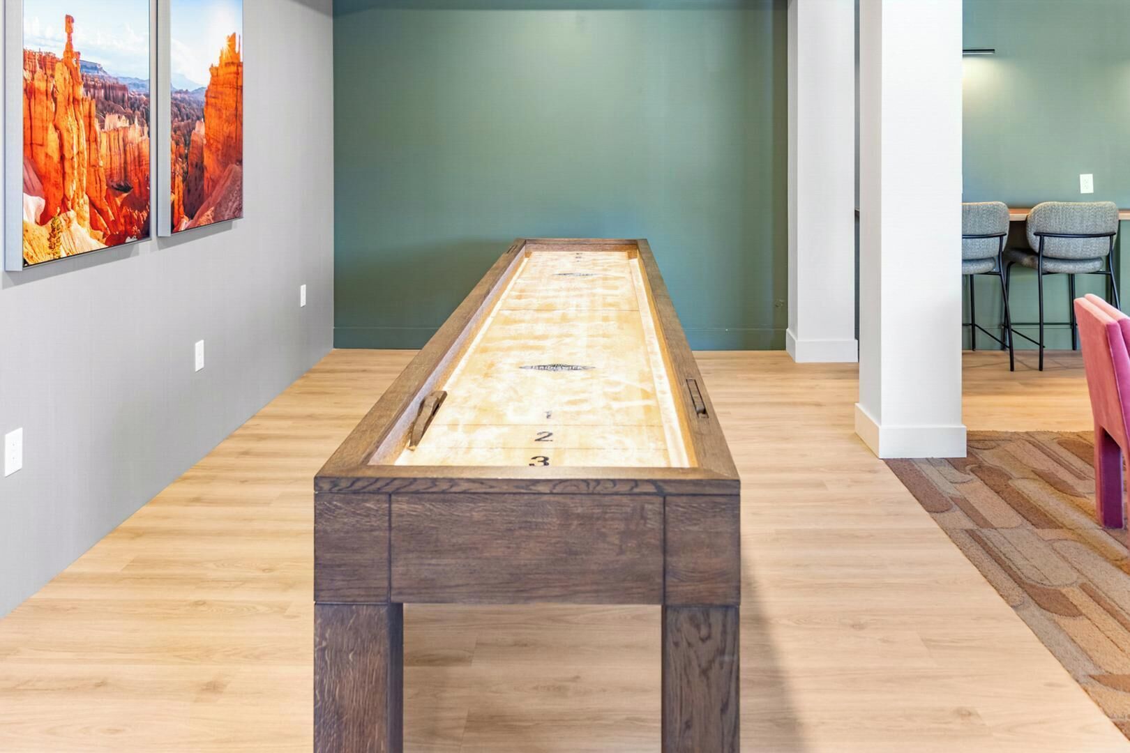 A pool table in a room with a wooden floor, green walls, and a chair in the background.