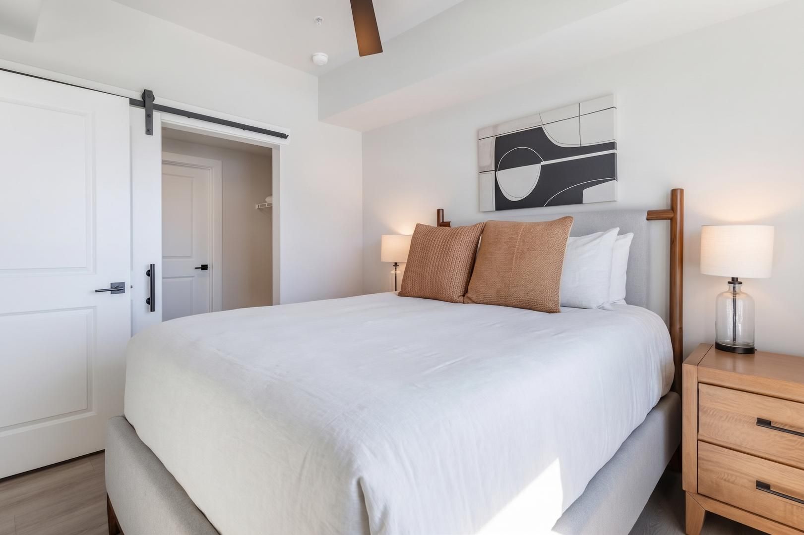 Une chambre à coucher comprenant un lit, des tables de chevet, une porte et une œuvre d’art accrochée au mur.