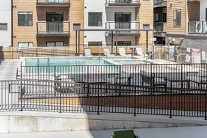 Ein Poolbereich auf dem Dach mit mehreren Pools, Liegestühlen und einem durch eine Umzäunung abgetrennten Bereich.