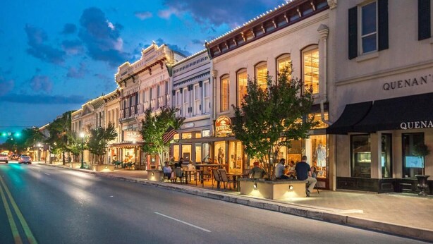 Une rue bordée de bâtiments historiques, dont un restaurant avec une terrasse et un hôtel-boutique.