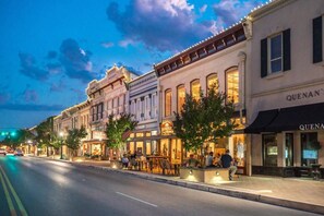 Una calle bordeada de edificios históricos, que incluye un restaurante con terraza y un hotel boutique.