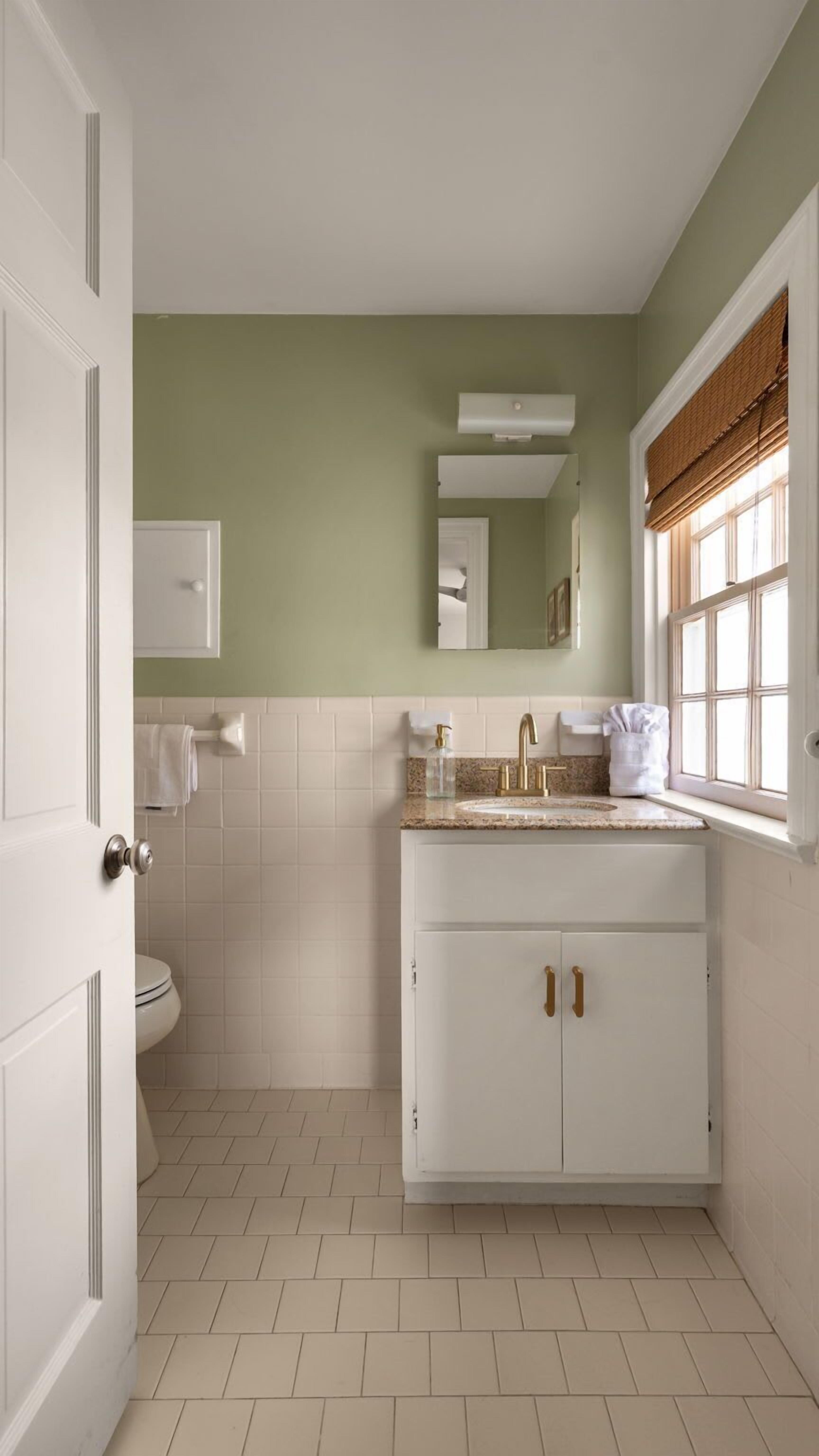 A bathroom with a white vanity, a toilet, and a window with a view.