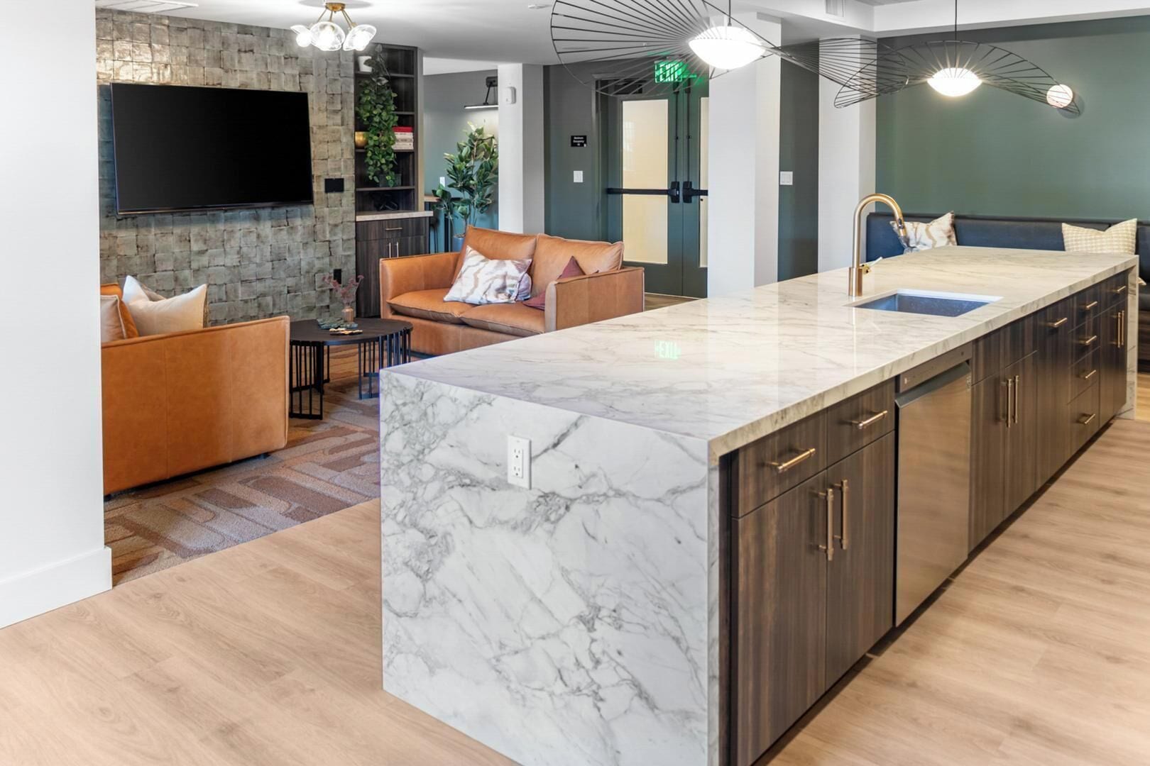 A modern kitchen with a marble island, dark wood cabinets, and a built-in sink.
