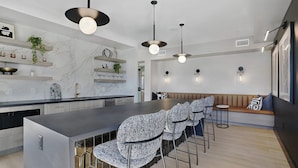 Une cuisine moderne avec un dosseret en marbre, un îlot central et des luminaires suspendus.